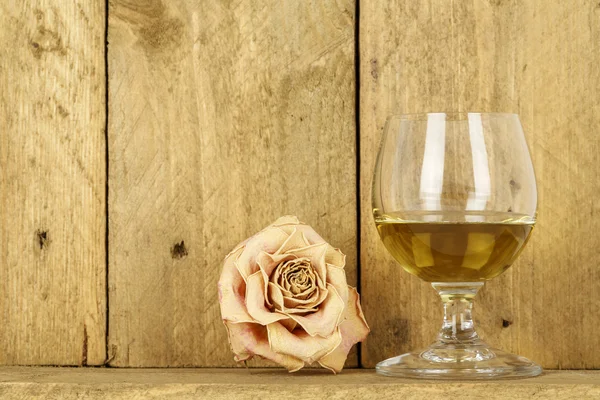 Glass of alcohol and dry rose — Stock Photo, Image