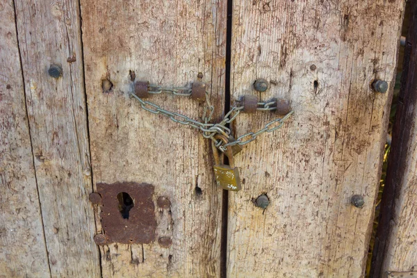 Vecchia porta in legno chiusa con catena e lucchetto — Foto Stock