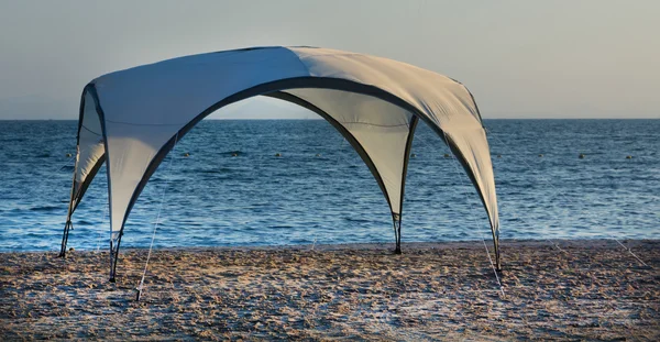 Moderní slunečník s čtyři nohy na pláži — Stock fotografie