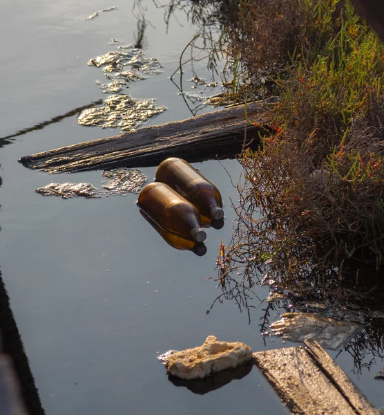 Botellas y suciedad en agua contaminada — Foto de Stock