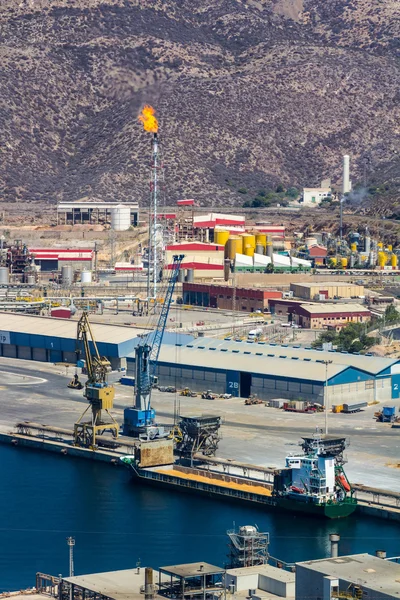 Cargo ship in a port with a fireplace and a refinery fire — Stock Photo, Image