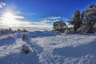 Mavi gökyüzü ve beyaz bulutları olan karlı bir yer.
