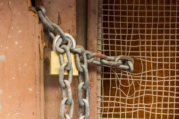 Cadeado na velha porta de madeira com corrente enferrujada — Fotografia de Stock