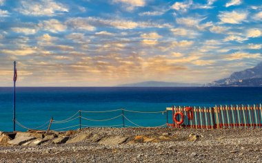 Liguria İtalya 'nın Ventimiglia kasabasındaki kayalık bir Akdeniz plajının manzara resmi.