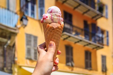 Ellerinde zanaat çikolatası ve arena vişneli dondurma, geleneksel renkli evler manzarası, Old Town Vieille Ville, Nice, Güney Fransa