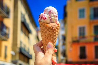 Ellerinde zanaat çikolatası ve arena vişneli dondurma, geleneksel renkli evler manzarası, Old Town Vieille Ville, Nice, Güney Fransa