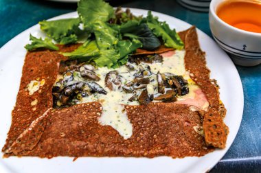 Geleneksel Breton karabuğday krepi veya jambon, peynir ve mantarlı galet, fincanda elma şarabı, Fransa 'nın Nice şehrinde bir restoranda öğle yemeği.