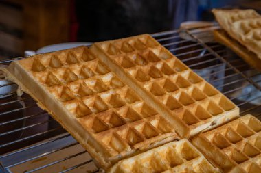 A freshly made golden Belgian waffle at the Strasbourg Christmas Market in France, festive snacks on display