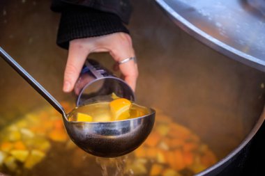 Tedarikçi sıcak portakallı beyaz şarabı kaynayan bir kaba dolduruyor, buhar geliyor, Fransa 'daki Strasbourg Noel Pazarı' nda festival sahnesi.