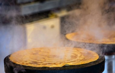 Satıcı, Fransa 'daki Strasbourg Noel Pazarı' nda özel bir tavada geleneksel ince bir Fransız krepi pişiriyor.