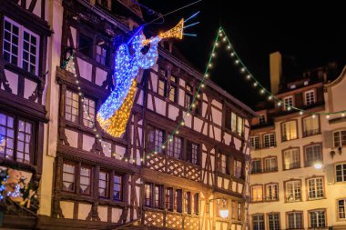 Fransa 'nın Strazburg kentindeki Noel Pazarı' nda şenlik dekorasyonları, melek süslemeleri ve arka planda tarihi yarım ahşap evler.