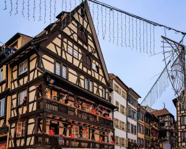 Fransa 'nın Strazburg kentindeki Noel Pazarı' nda şenlik dekorasyonları, melek süslemeleri ve arka planda tarihi yarım ahşap evler.