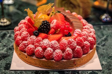 Kırmızı böğürtlenli tart, çilek, üzümlü frengi üzümü, üzerine bitki üzümü konmuş Noel zamanı, Strasbourg, Fransa 'daki bir zanaatkar fırında.