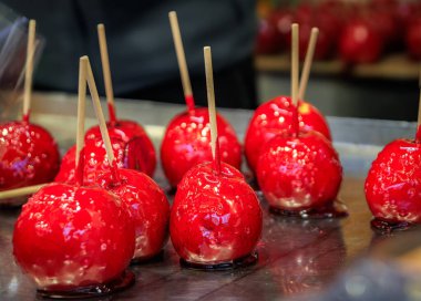 Parlak kırmızı Pommes d 'amour Şeker Elmaları sert şekerle kaplanmış karamel Strasbourg, Fransa' daki bir Noel marketinde çubuklarda sergileniyor.