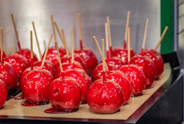 Parlak kırmızı Pommes d 'amour Şeker Elmaları sert şekerle kaplanmış karamel Strasbourg, Fransa' daki bir Noel marketinde çubuklarda sergileniyor.