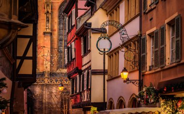 Tarihi yarım ahşap evlerdeki şenlikli dekorasyon ve süsler Eski Şehir, Colmar, Alsace, Fransa 'daki Noel Pazarı sırasında gün batımında parlıyor.