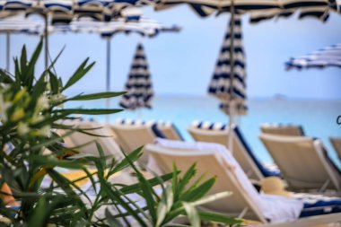 Bulanık çizgili şemsiyeler Fransa 'nın güneyindeki Nice kentinde Akdeniz' in turkuaz suyu olan gezinti güvertesi boyunca bir sahilde.