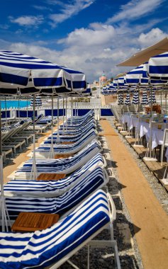 Akdeniz 'in Nice' teki turkuaz suyu, Fransa 'nın Cote d' Azur şehrinde sahil şemsiyeleri ve sandalyeli çakıl taşı plajı.