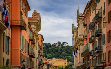 Bulutlu bir günde Fransa 'nın eski Nice kasabasında geleneksel Akdeniz evlerinin cephelerinde süslü balkonları ve tahta panjurları vardı.