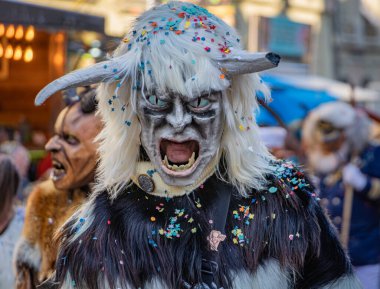 Bern İsviçre - 8 Mart 2025 'te İsviçre' deki Fasnacht karnavalında boynuzlu ahşap maskeli, Tschaggatta giysili bir adam