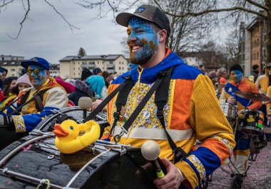 Zug, İsviçre - 1 Mart 2025: Guggenmusik renkli kostümler içinde bando yürüyüşü ve Fasnacht kış karnaval geçit töreninde yüz boyama gösterileri