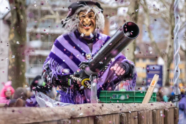 Zug, İsviçre - 1 Mart 2025 Fasnacht kış karnaval geçidinde elinde bir konfeti tabancasıyla cadı kıyafeti ve maske giymiş bir kostümcü