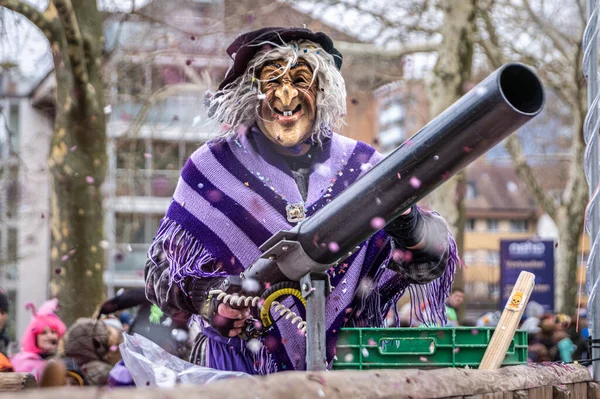Zug, İsviçre - 1 Mart 2025 Fasnacht kış karnaval geçidinde elinde bir konfeti tabancasıyla cadı kıyafeti ve maske giymiş bir kostümcü