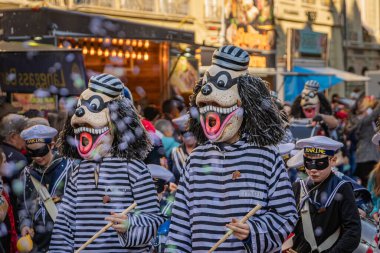 Bern, İsviçre - 1 Mart 2025: Guggenmusik renkli kostümler içinde bando yürüyüşü ve Fasnacht kış karnavalı geçit töreninde yüz boyama gösterileri