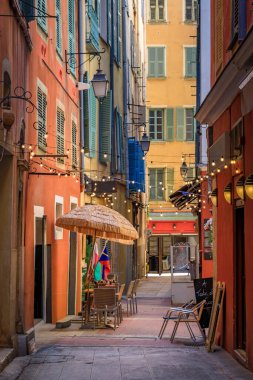 Al fresco masaları, renkli geleneksel evleri olan, Fransa 'nın güneyinde, pitoresk dar bir sokaktaki açık hava restoranında müşterileri bekliyor.