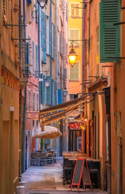 Al fresco masaları, renkli geleneksel evleri olan, Fransa 'nın güneyinde, pitoresk dar bir sokaktaki açık hava restoranında müşterileri bekliyor.