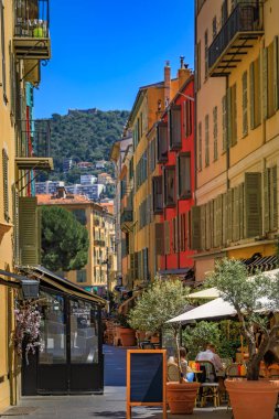 Al fresco masaları, renkli geleneksel evleri olan, Fransa 'nın güneyinde, pitoresk dar bir sokaktaki açık hava restoranında müşterileri bekliyor.