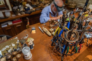 Silversmith working with tools on a jewelers bench in a traditional artisanal silversmith workshop and studio in Centro Storico in Florence, Italy