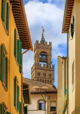 Arnolfo Palazzo Kulesi dar sokakların ve İtalya 'nın Floransa şehrinde mavi bir gökyüzünün altında yeşil panjurlu tarihi binaların üzerinde yükseliyor.