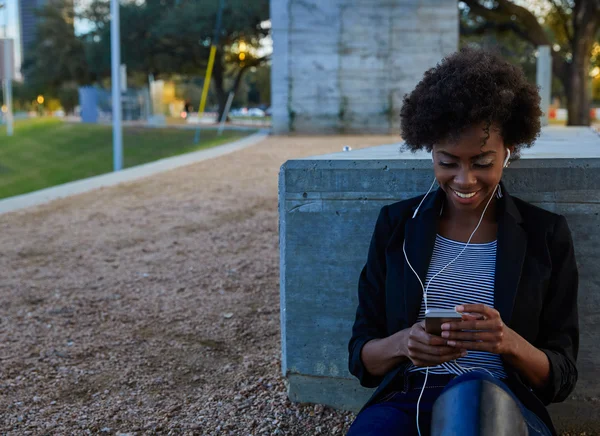 Woman with smartphone sitting in the park — Stock Photo, Image