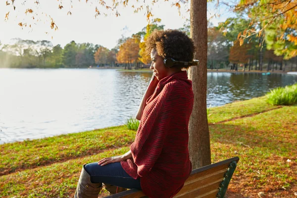 Donna che ascolta musica nel parco autunnale — Foto Stock