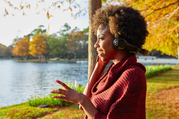 Женщина слушает музыку в осеннем парке — стоковое фото