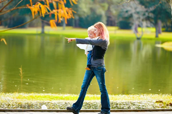 Menina criança e mãe andando no lago do parque — Fotografia de Stock