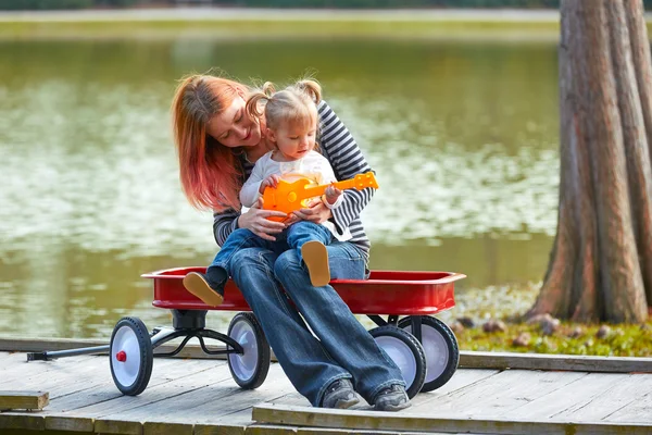 Mother and daughter playing toy guitar in a lake — Stock Photo, Image