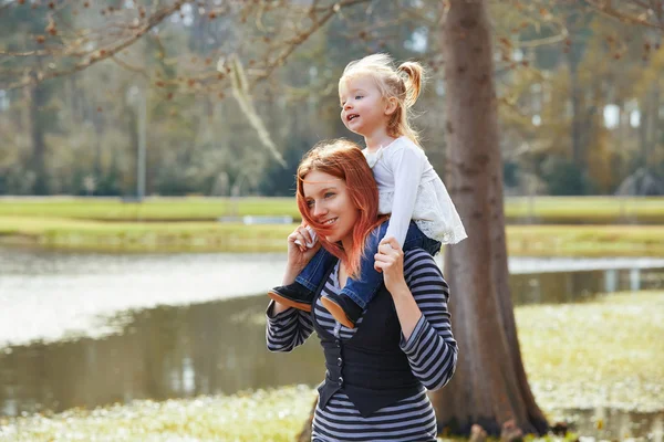 Mother holding daughter in shoulders in a lake — Stock Photo, Image
