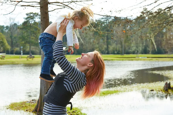 Mother playing throwing up baby girl in a lake — Stock Photo, Image