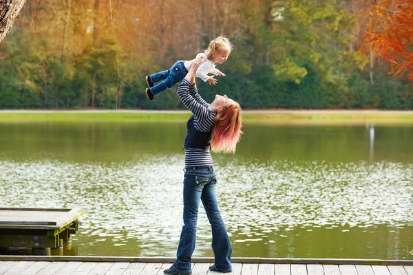 Mãe jogando vomitar bebê menina em um lago — Fotografia de Stock