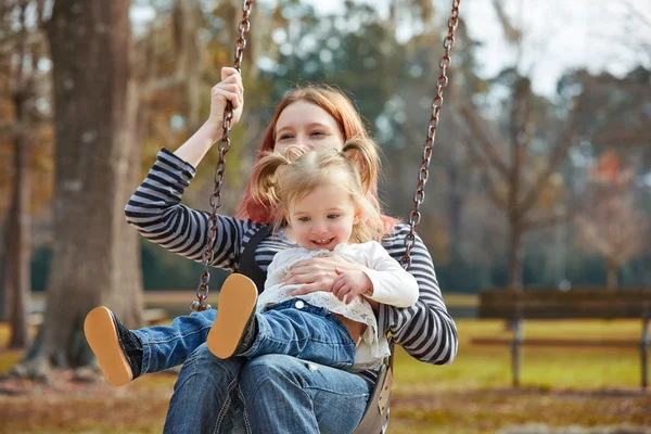 Mor och dotter i en gunga i parken — Stockfoto