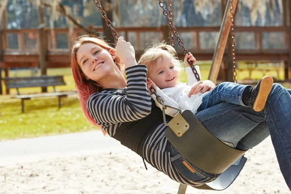 Mor och dotter i en gunga i parken — Stockfoto