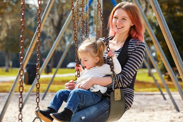 Mère et fille dans une balançoire au parc — Photo