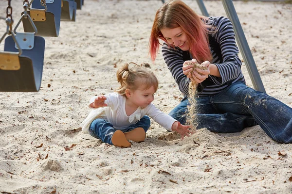 Moeder en dochter spelen met zand in park — Stockfoto