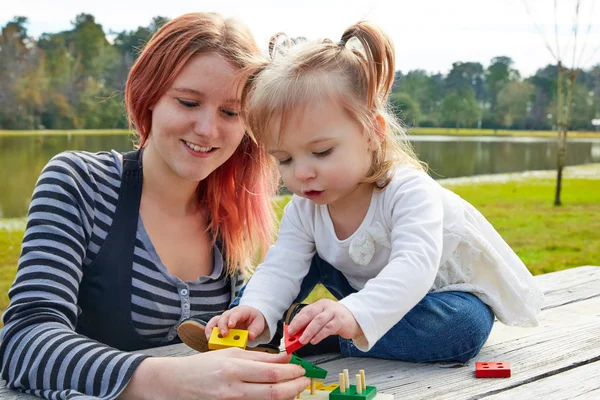 Mor och dotter leker med figurer i park — Stockfoto