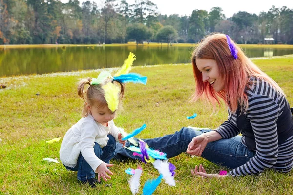 Mãe e filha brincando com penas no parque — Fotografia de Stock