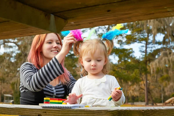 Moeder en dochter tekening van kleuren in een park — Stockfoto