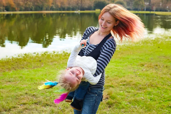 Mãe e filha brincando com penas no parque — Fotografia de Stock