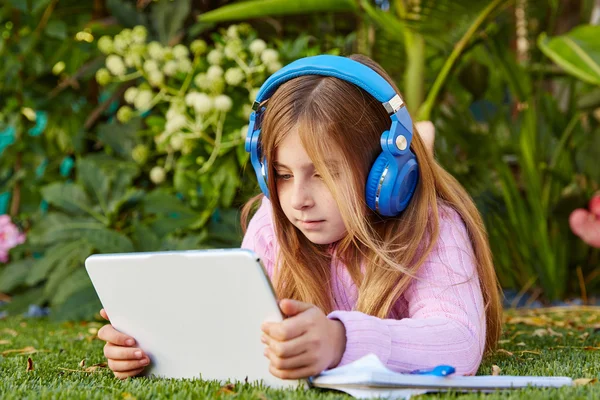 Blondes Mädchen mit Tablet-PC auf Rasen liegend — Stockfoto